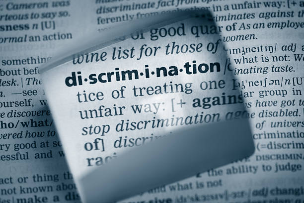The Dictionary definition of the word “discrimination” photo taken through magnifying glass from a page of a dictionary with selective focus.