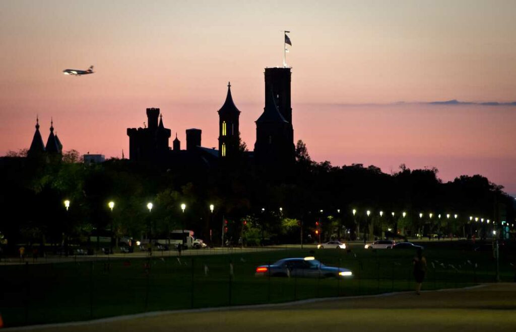 US - POLITICS - GOVERNMENT- SHUTDOWN A passenger plane flies in the sky above the Smithsonian Institution Building -- "The Castle" -- on the eve of a possible government shutdown as Congress battles out the budget in Washington, DC, September 30, 2013. In case of a government shutdown all Smithsonian museums and the National Zoo will be closed to visitors. AFP PHOTO/ MLADEN ANTONOV (Photo credit should read MLADEN ANTONOV/AFP via Getty Images)