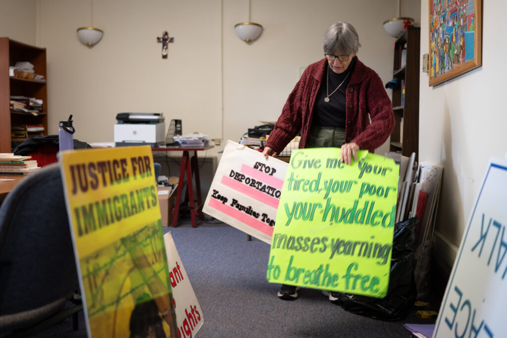 Benedictine Sister Anne McCarthy rifles through demonstration signs in Erie on Monday, March 30, 2026. (Joed Viera for Spotlight PA)